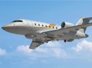 A white private jet with yellow and gray stripes is flying against a blue sky with scattered clouds.