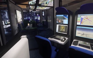 A modern control room with multiple computer monitors displaying maps and data, blue chairs, and glass walls reflecting additional screens and equipment in the background.