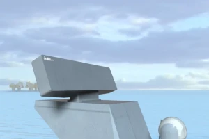 A close-up of a modern, angular radar system mounted on a vessel, with calm blue water and a cloudy sky in the background. Some offshore structures are visible in the distance.