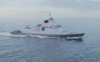 A gray naval warship sails on the open sea under a cloudy sky, displaying the Philippine flag on its mast.
