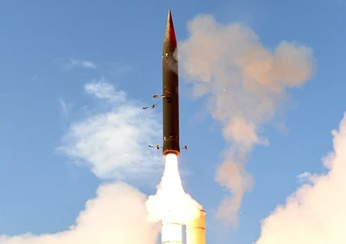 An anti ballistic missile is launching vertically into a clear blue sky, with bright flames and smoke erupting from its base.