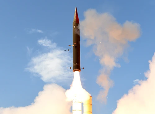 An anti ballistic missile is launching vertically into a clear blue sky, with bright flames and smoke erupting from its base.