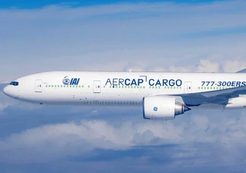 A white AerCap Cargo 777-300ERSF airplane, showcasing advanced aircraft systems integration, soars above the clouds with IAI and AERCAP CARGO logos clearly visible on its side.