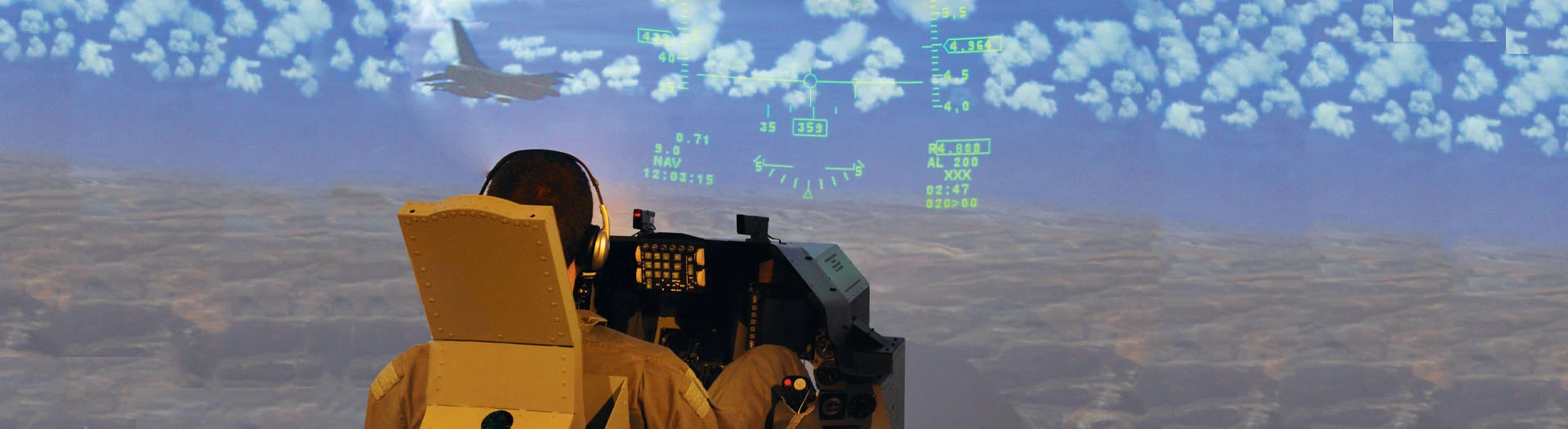 A person sits in a flight simulator cockpit, facing a large screen displaying a jet and flight HUD graphics above a desert landscape, experiencing a realistic flying training system.