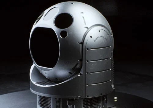 A spherical, metallic object labeled MOSP5000 with several circular openings and a smooth, futuristic surface sits on a base against a dark background. The structure appears to be part of advanced technology or equipment.