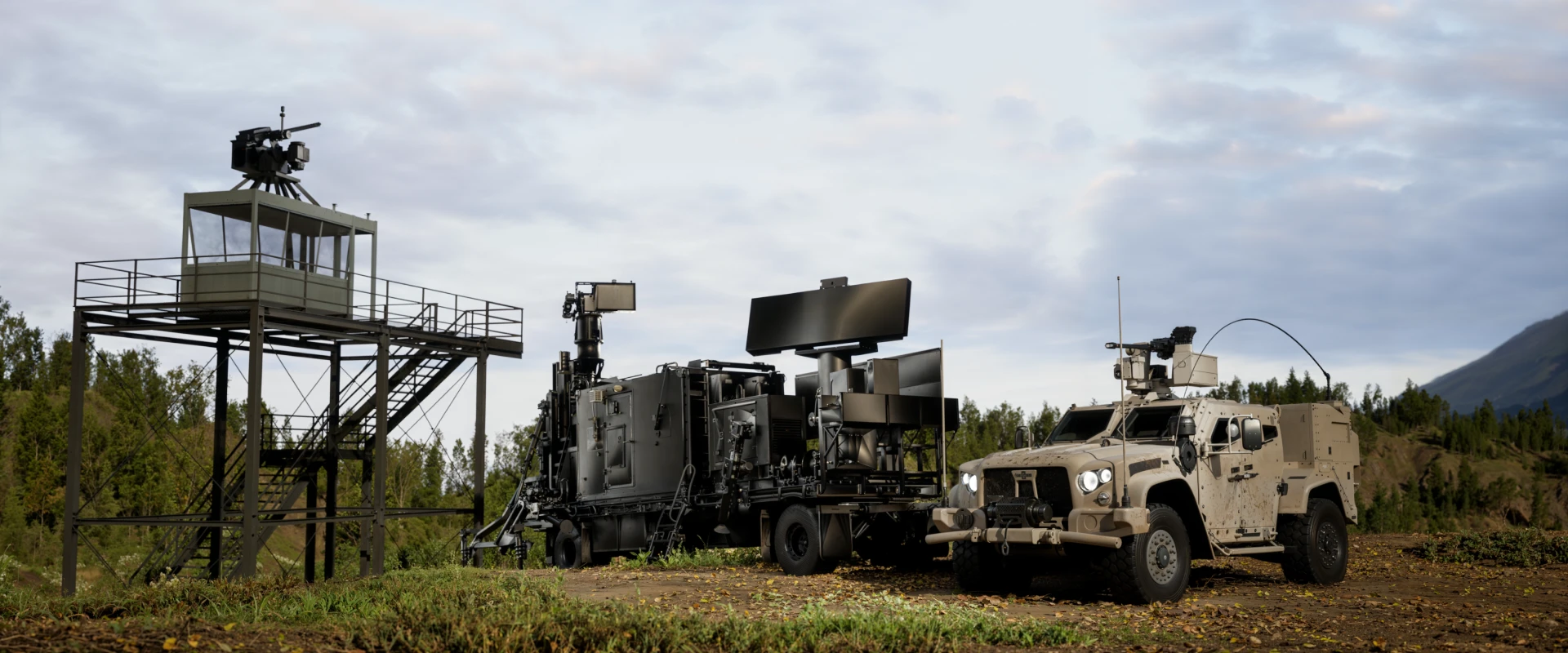A military surveillance setup featuring a watchtower, a truck with large radar screens for hard kill C-UAS operations, and an armored vehicle, all positioned outdoors on a grassy field with trees and a cloudy sky in the background.