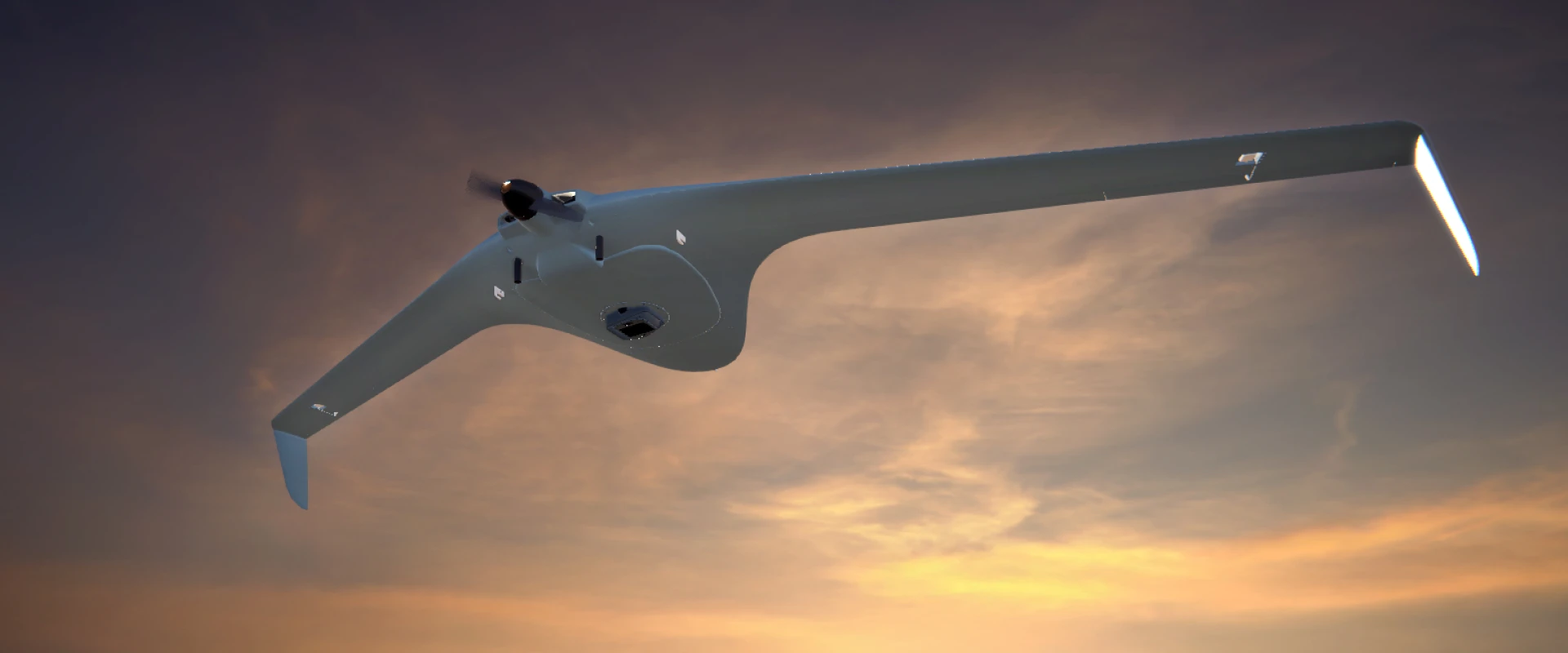 A sleek, white WASP drone with a wide wingspan and rear propeller soars against a dramatic sunset sky ablaze with orange and purple hues.