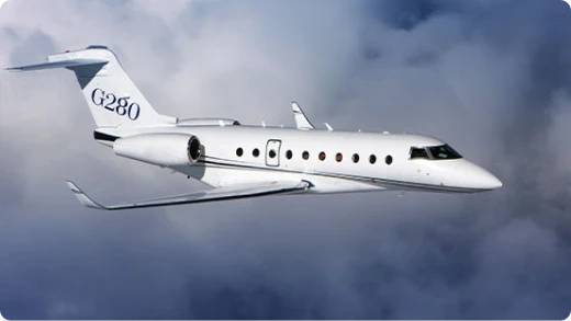 A white Gulfstream G280 private jet is flying through the sky with clouds in the background. The aircraft has G280 written on its tail.