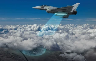 A fighter jet equipped with an AESA GMTI reconnaissance system flies above the clouds, emitting a blue beam of light downward toward a circular glowing area on the ground below.