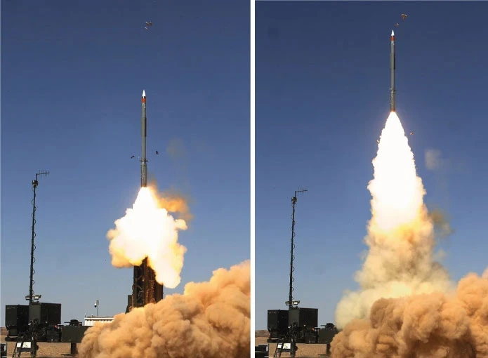 Two side-by-side photos show an IAI rocket launching vertically, leaving a trail of smoke and flames against a clear blue sky, with ground equipment and antennas visible below.