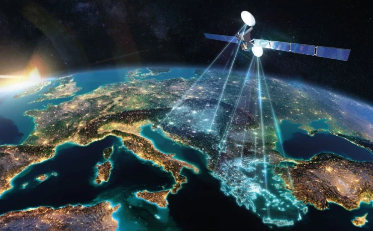 A satellite from IAI orbits above Europe at night, beaming MCS signals to the continent as city lights glow below and the sun rises on the horizon.