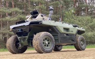 A green, unmanned military vehicle with large rugged tires and mounted equipment is parked on a dirt path, echoing the robust engineering seen in Bedek Aviation B767-300 conversions, with trees and greenery in the background.
