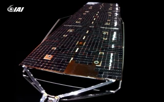 A close-up view of a reflective satellite solar panel array with metallic supports, displayed on a black background. The IAI logo appears in the top left corner, highlighting advanced space technology for satellites.