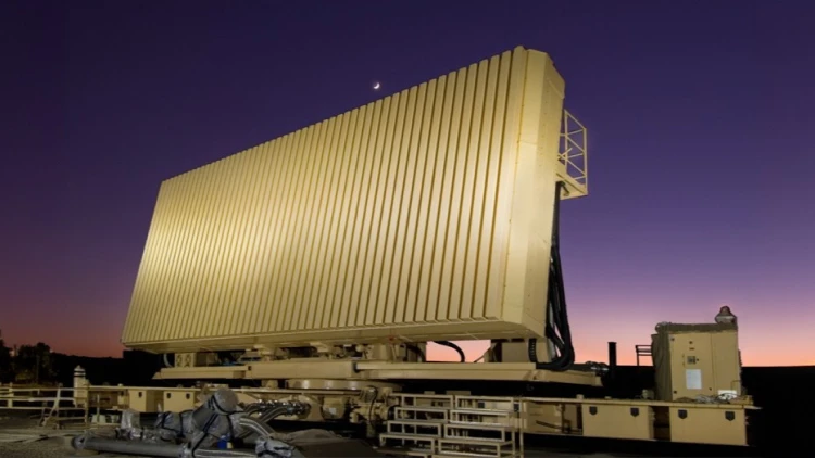 Large, rectangular IAI military radar system with vertical slats is mounted on a platform at dusk, with a crescent moon visible in the purple and orange sky. Railings and equipment surround the impressive radar structure.